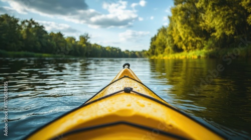 Kayaking on a calm river through a forest, with only the bow of the yellow kayak visible in the foreground. photo