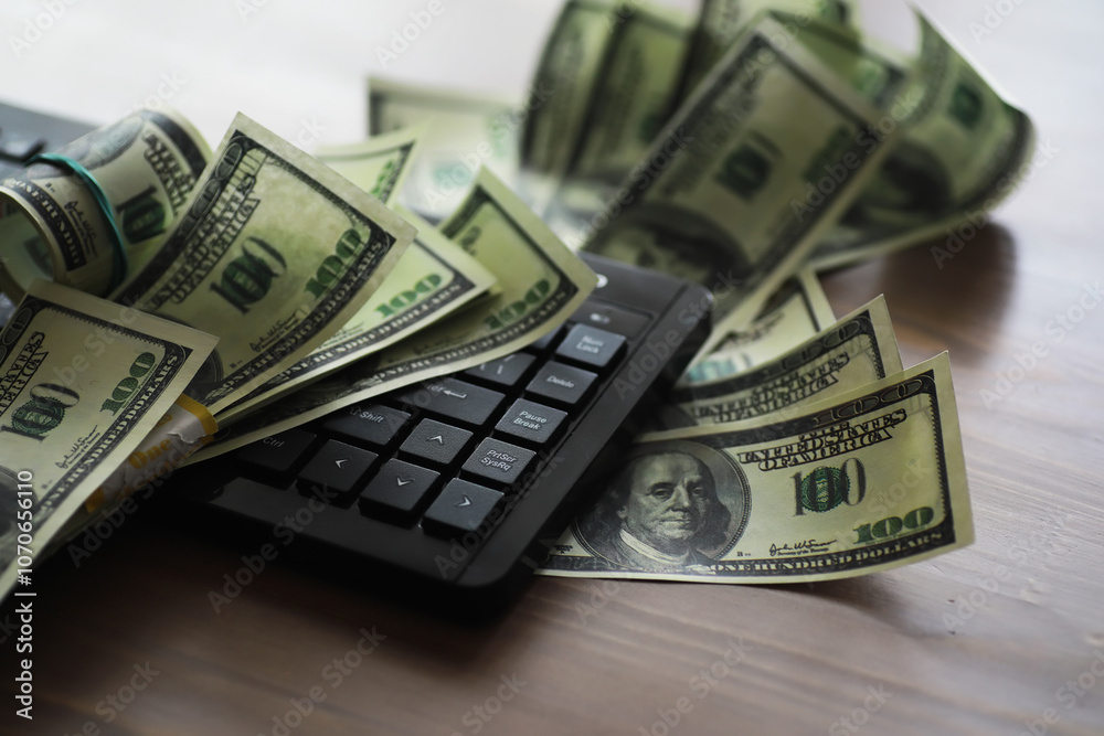 Computer keyboard and a scattering of 100 dollar bills on the table. The work of a programmer and blogger on the Internet. Computer keyboard and a scattering of 100 dollar bills on the table. The work of a programmer and blogger on the Internet.