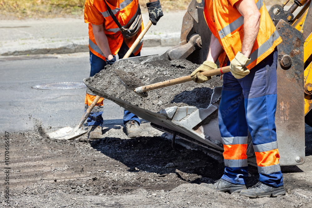 Construction workers repairing a city road under bright sunlight with machinery and tools