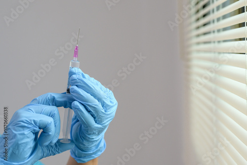 A medical professional is preparing a syringe for patient care while holding a vaccine that is ready to be injected.