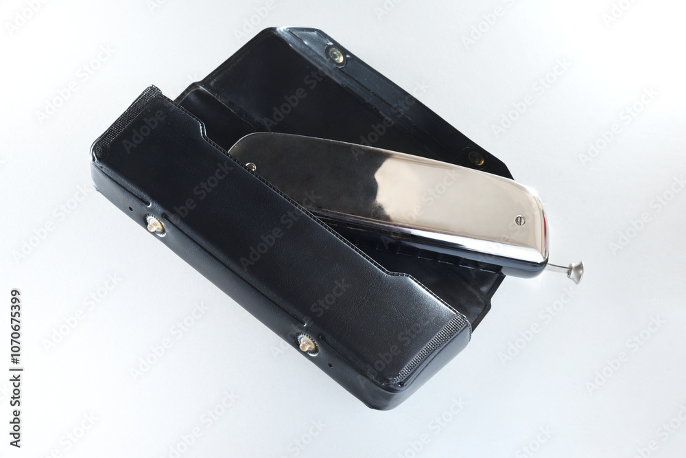 Metal chromatic harmonica in its plastic protective case elevated view Metal chromatic harmonica in its plastic protective case elevated view