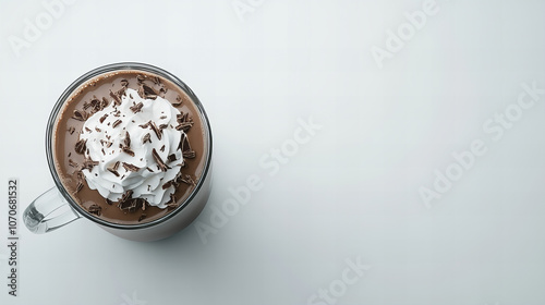 Delicious hot chocolate topped with whipped cream and chocolate shavings served in a clear glass on a minimalist surface