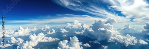 A view from above, looking down on a vast expanse of fluffy white clouds, illuminated by the sun, with a clear blue sky stretching out in the distance