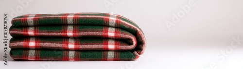 A folded plaid blanket in festive colors, showcasing a cozy and inviting appearance, ideal for winter comfort and home decor.