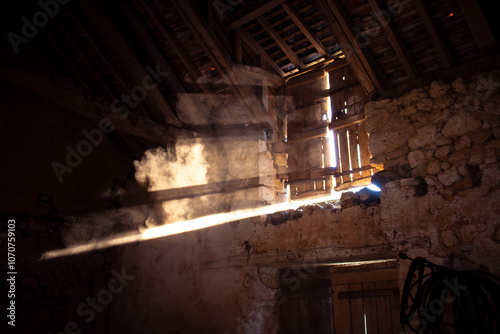 Vielle grange sombre avec de la lumière qui passe entre les planches de bois d'une fenêtre.  photo