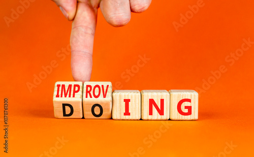 Doing or improving symbol. Businessman turns wooden cubes and changes the word Doing to Improving. Beautiful orange table orange background. Educational business doing or improving concept. Copy space