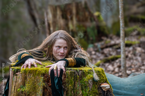 Woman leaning on tree trunk in forest. Shallow depth of feld