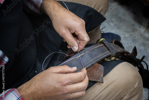 A saddler craftsman restores and creates animal harnesses and tack with leather. He cuts, glues, sews, paints.