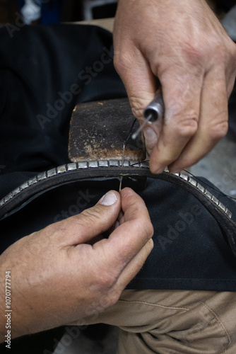 A saddler craftsman restores and creates animal harnesses and tack with leather. He cuts, glues, sews, paints. photo