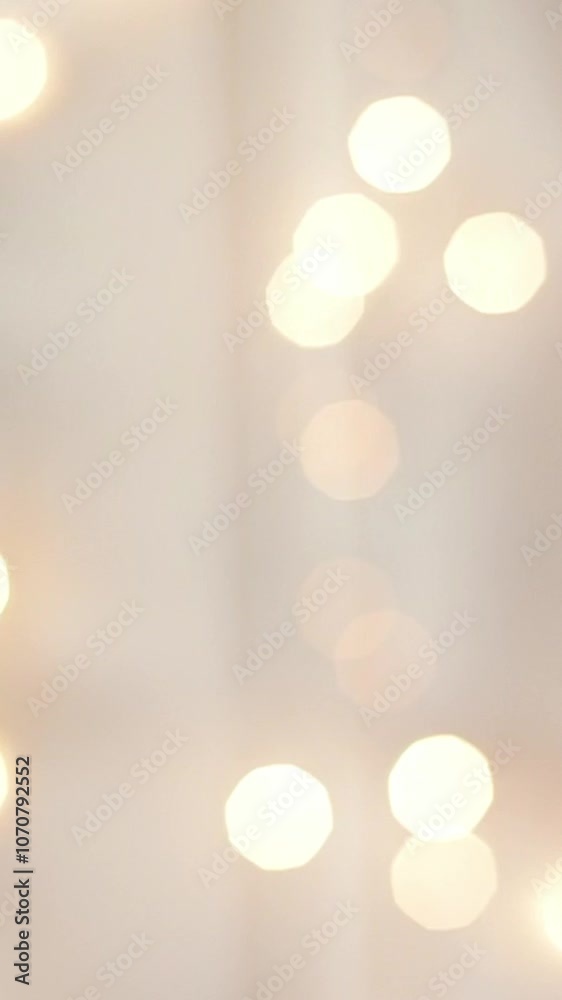 Blurred golden shining lights on white background. Abstract glowing bokeh. Christmas and New Year holidays background. Vertical shot