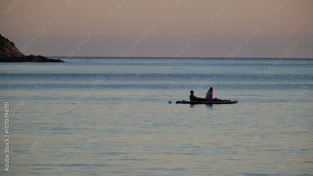Naklejka premium Sunset on the Côte d'Azur with people on paddle enjoying the sea