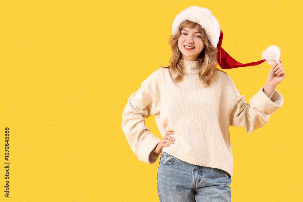 Young woman in Santa hat on yellow background Young woman in Santa hat on yellow background