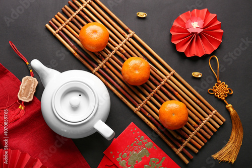 Teapot with mandarins and oriental symbols on black background. New Year celebration photo