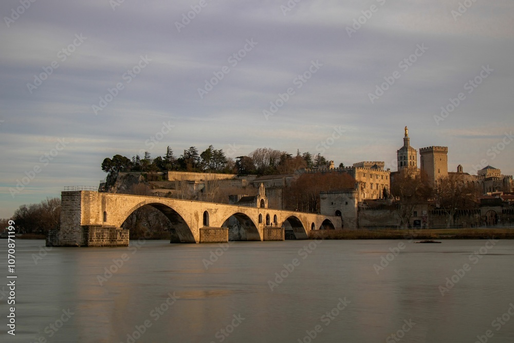Pont Saint-Benezet bridge and Avignon cityscape under a serene sky at dusk in Provence, France Pont Saint-Benezet bridge and Avignon cityscape under a serene sky at dusk in Provence, France