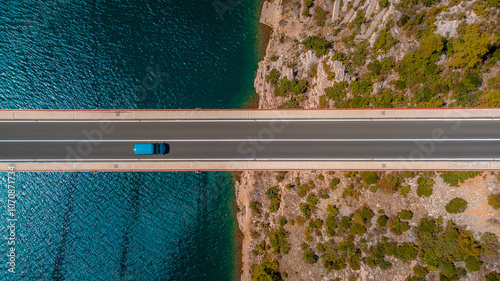 Top down view blue car driving over the bridge over the sea. Background and icon of travel, car journey to discover a country.