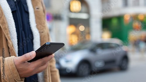 Man using smartphone app for electric car rental service in city
