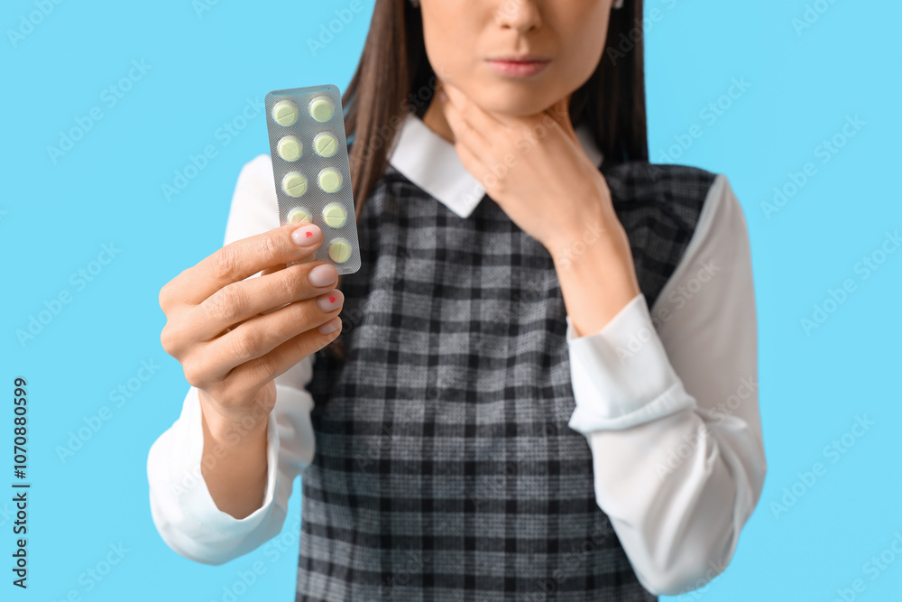 Young woman with pills for sore throat on blue background, closeup Young woman with pills for sore throat on blue background, closeup