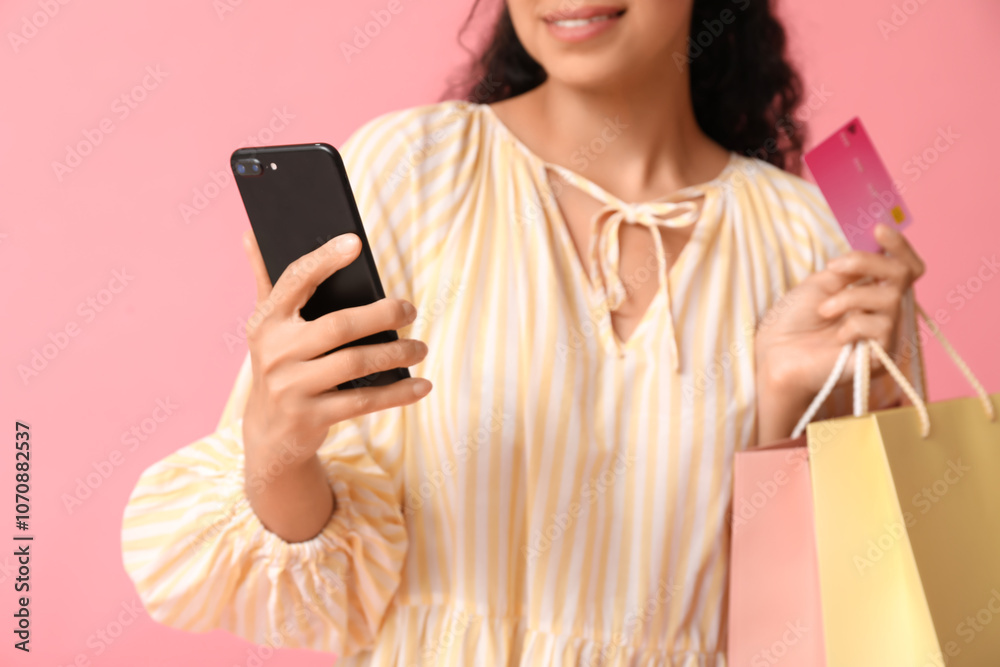 Young woman with mobile phone, shopping bags and credit card on pink background Young woman with mobile phone, shopping bags and credit card on pink background