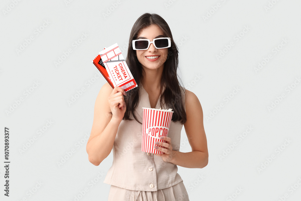 Young pretty woman in 3D cinema eyeglasses with popcorn bucket and tickets on white background Young pretty woman in 3D cinema eyeglasses with popcorn bucket and tickets on white background