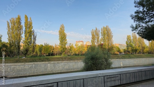 Quadro su tela Sunny Riverside with Poplar Trees and Stone Embankment