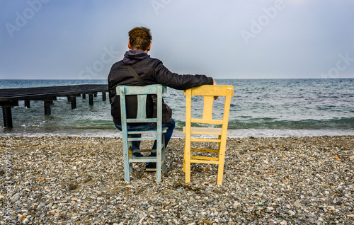 Man Sitting on the Beach with Empty Chair 