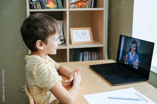 Child happily engaging in homeschooling through online education, utilizing a laptop for virtual classroom meetings and video conferences with teachers