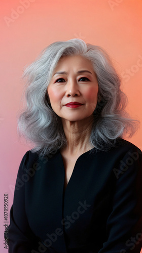 Professional mature businesswoman with gray hair posing against pink background in smart attire