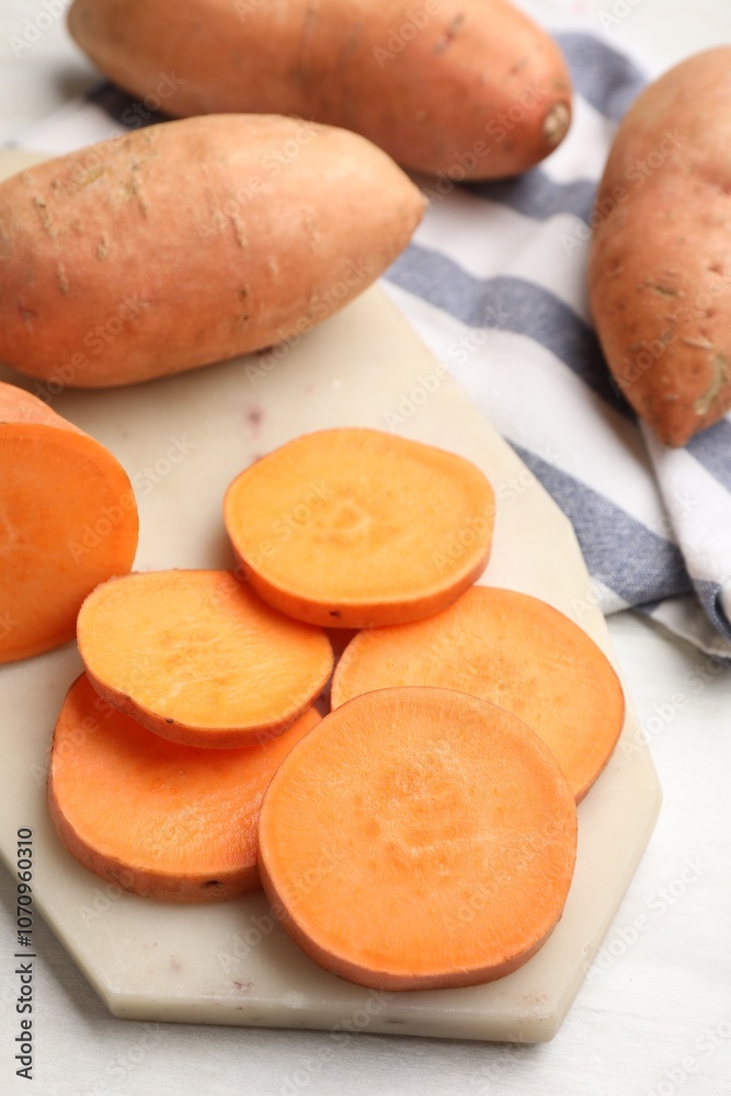Fresh sweet potatoes and kitchen towel on white table, closeup Fresh sweet potatoes and kitchen towel on white table, closeup