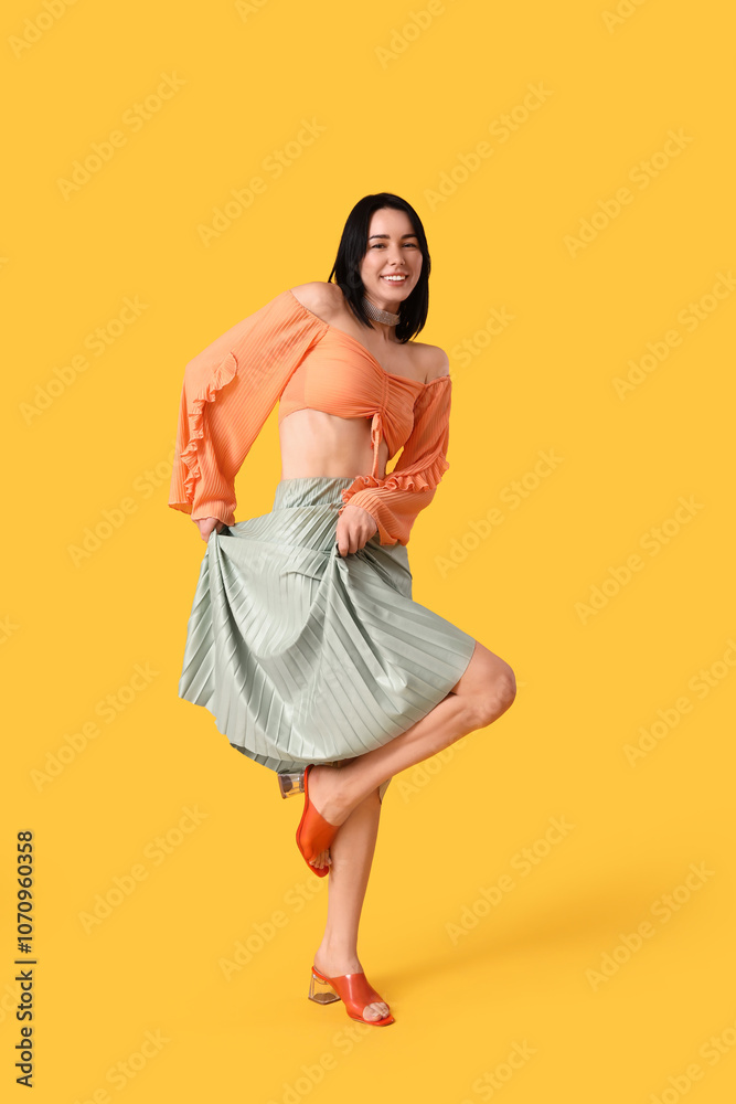 Naklejka premium Happy young woman in skirt dancing on yellow background