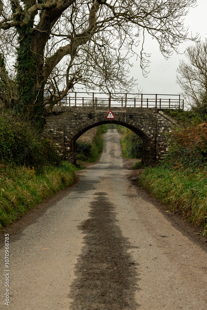 Narrow country road passing under stone bridge in autumn Narrow country road passing under stone bridge in autumn