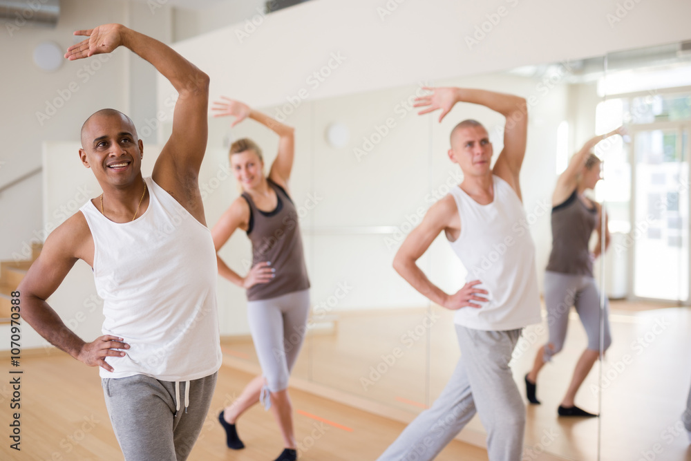 Cheerful Latino practicing vigorous lindy hop movements in group dance class Cheerful Latino practicing vigorous lindy hop movements in group dance class