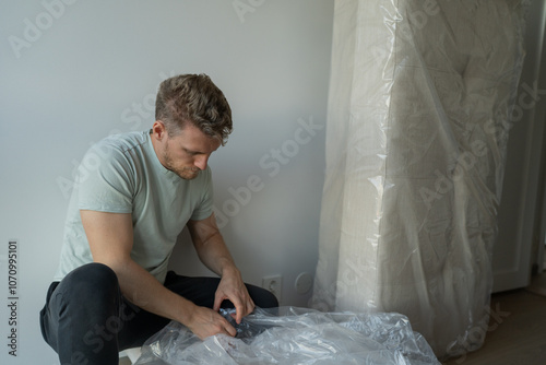 man opens new sofa and removes it from cellophane