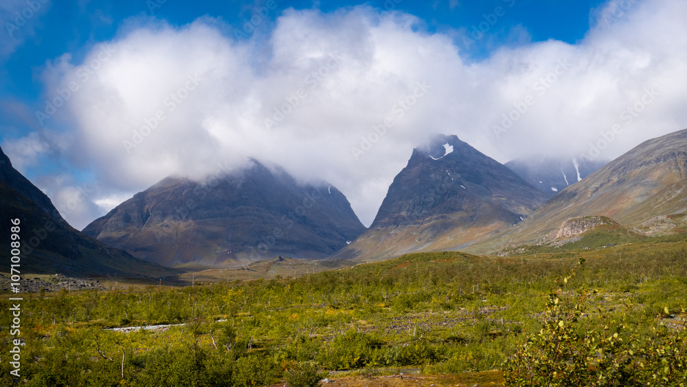 Fototapeta premium Breathtaking view to the Kebnekaise peak hidden in the clouds and scenic mountain valley shows beautiful swedish arctic nature in lapland during september when hiking to the arctic wilderness.
