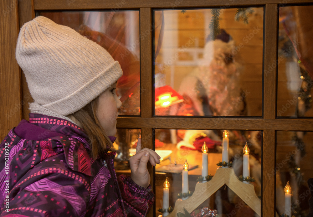 The girl looks through the window into Santa's house. Father Christmas. New Year and Christmas celebrations. The girl looks through the window into Santa's house. Father Christmas. New Year and Christmas celebrations.