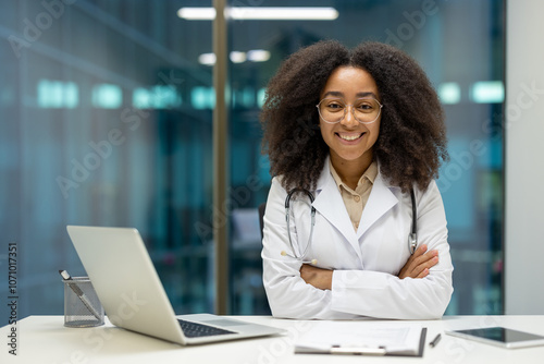 Confident African American female doctor in white coat with smile arms crossed in modern office. Afro hair, glasses on, with laptop, clipboard. Professional medical setting, healthcare concept. Free Download Confident African American female doctor in white coat with smile arms crossed in modern office. Afro hair, glasses on, with laptop, clipboard. Professional medical setting, healthcare concept. - GFXLoad