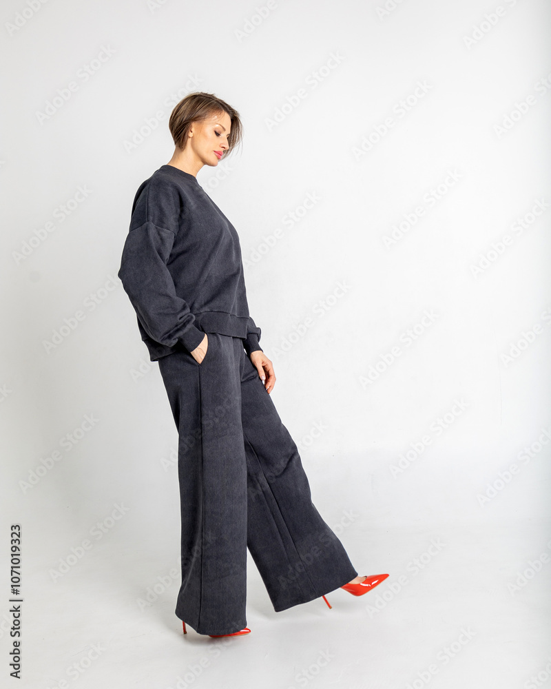 Portrait beautiful woman of model appearance. Girl in black jumper and trousers, red shoes on grey background. Pretty female with trendy makeup posing in studio. Vertical photo. High quality photo Portrait beautiful woman of model appearance. Girl in black jumper and trousers, red shoes on grey background. Pretty female with trendy makeup posing in studio. Vertical photo. High quality photo