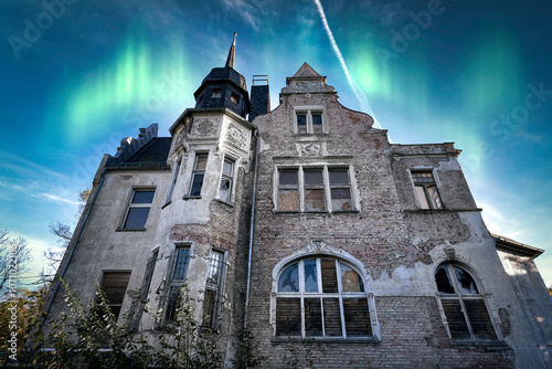 erlassene Villa mit mystischem Polarlicht am Nachthimmel photo