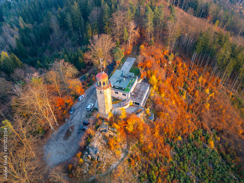 The lookout tower on Prosec Ridge near Jablonec nad Nisou stands surrounded by vibrant autumn foliage during a serene sunset, offering breathtaking views of the Jizera Mountains. photo