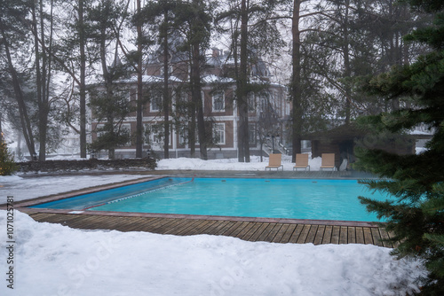 Outdoor swimming pool with warm water. Winter wellness spa resort with hot outdoor swimming pool with thermal water, foggy weather