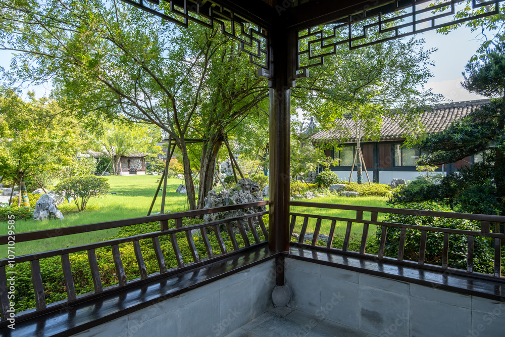 A peaceful view from a traditional Chinese covered veranda or gazebo, ornate wooden railings, and lattice overlooking a landscaped oriental garden. A rest area in the park with classic architecture. A peaceful view from a traditional Chinese covered veranda or gazebo, ornate wooden railings, and lattice overlooking a landscaped oriental garden. A rest area in the park with classic architecture.