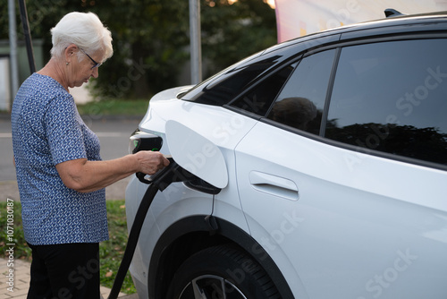 Senior Woman Charging Electric Car at EV Station