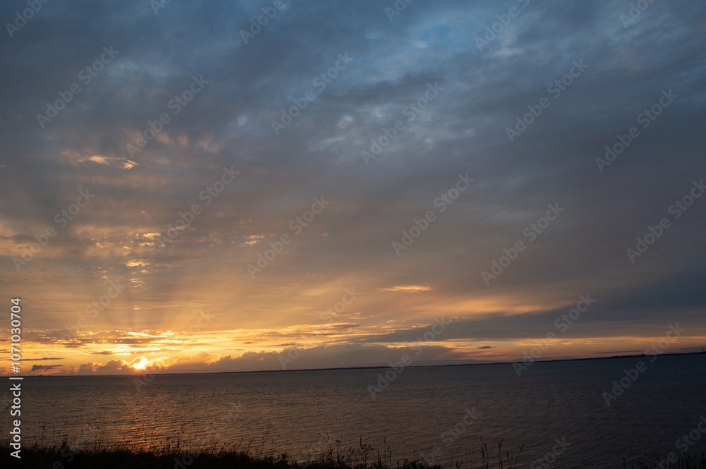 Beautiful sunset in cloudy sky by the ocean Beautiful sunset in cloudy sky by the ocean