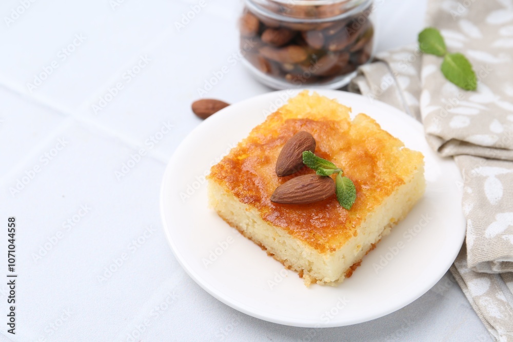 Slice of tasty semolina cake served on white tiled table, closeup. Space for text Slice of tasty semolina cake served on white tiled table, closeup. Space for text