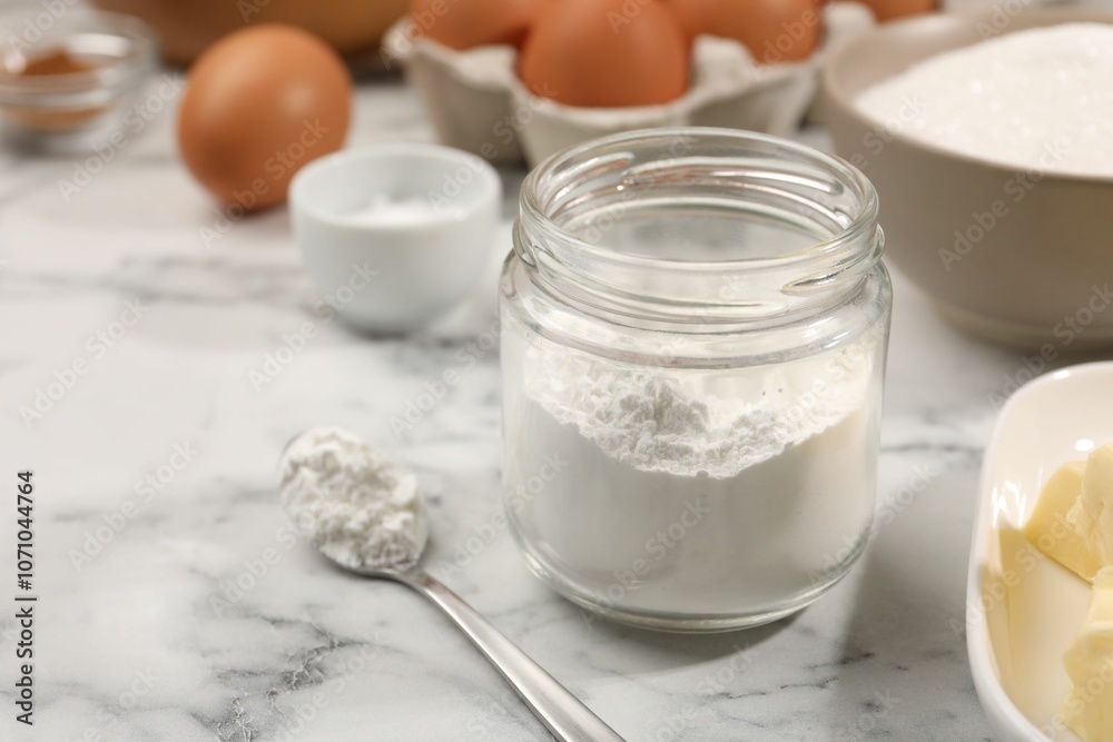 Baking powder in jar and other products on white marble table, closeup Baking powder in jar and other products on white marble table, closeup