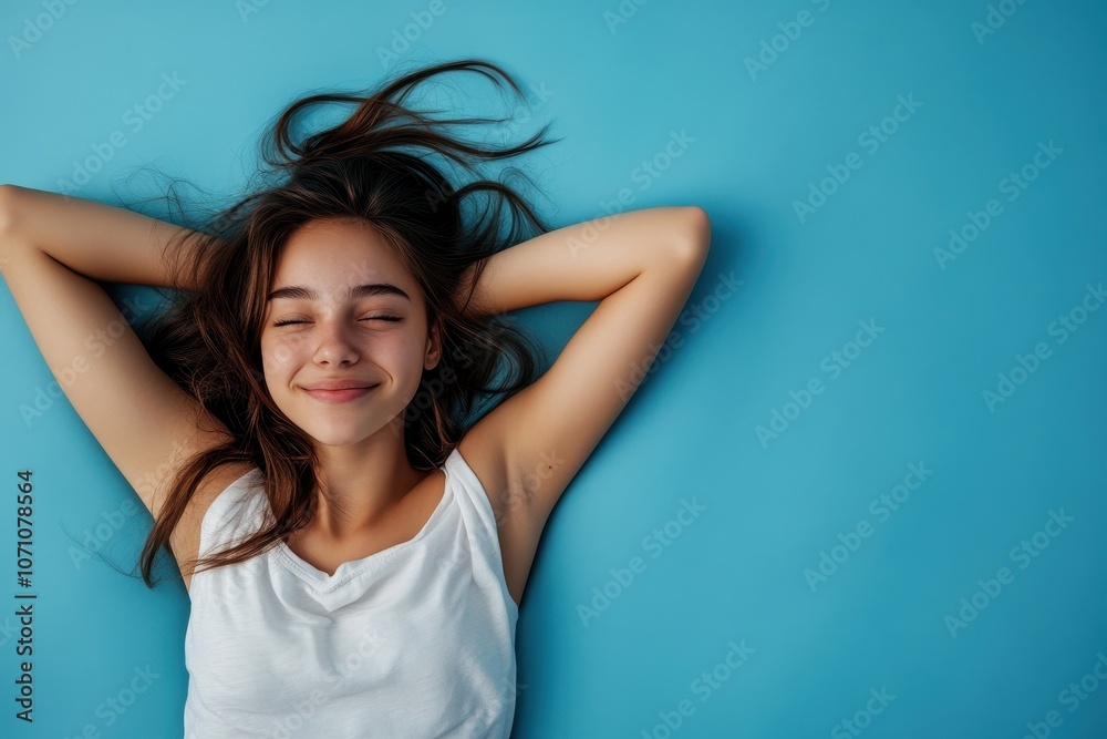 Large image of a cheerful stylish young girl about to sleep against a blue backdrop Large image of a cheerful stylish young girl about to sleep against a blue backdrop
