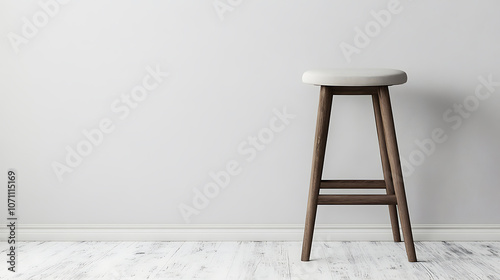 A backless seat bar stool with upholstery sits against a gray backdrop in an empty white room