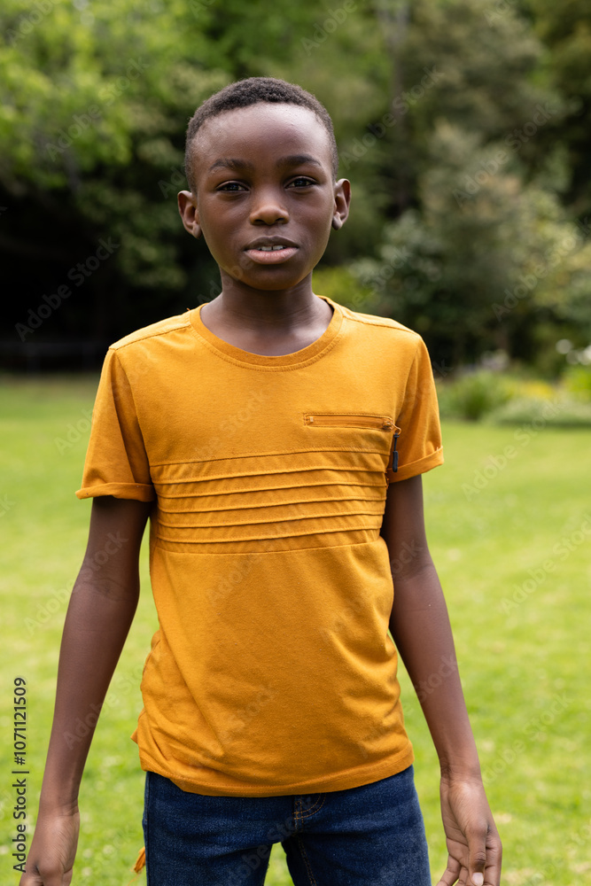 boy standing in park wearing yellow shirt, enjoying outdoors boy standing in park wearing yellow shirt, enjoying outdoors