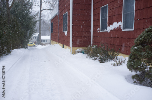 snowing in the driveway by a red suburban house in winter	