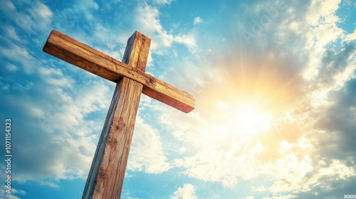 Wooden cross illuminated by sunlight against a blue sky with clouds at dawn