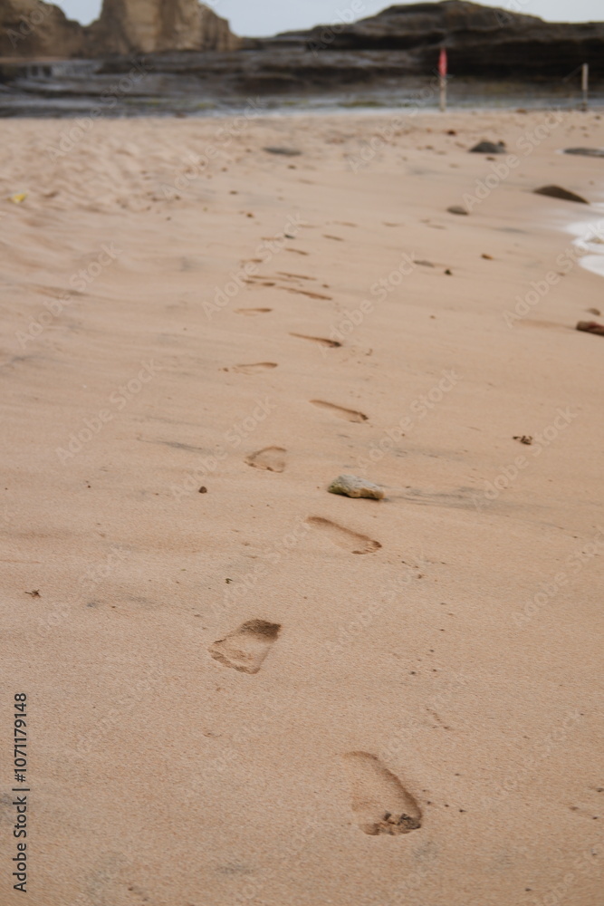 A trail of footprints stretches along the sandy beach A trail of footprints stretches along the sandy beach